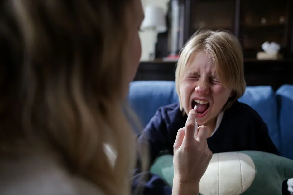 Parent giving medicine to a sick child on the couch